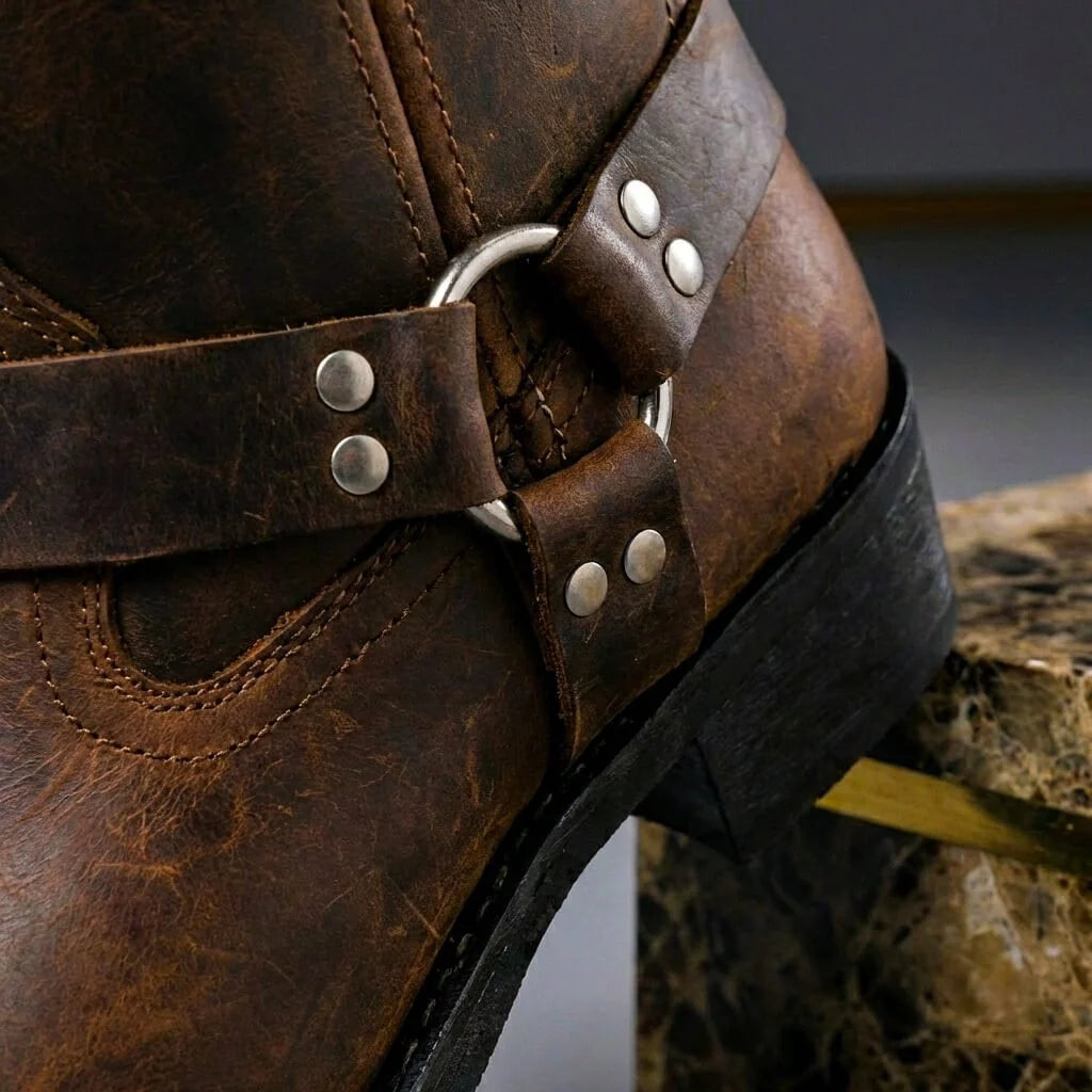 Close up of the riveted harness strap and metal ring on cognac brown leather boots