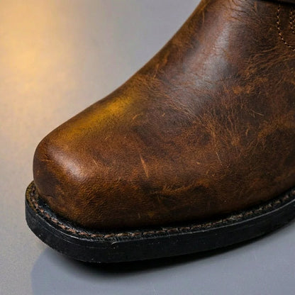 Square toe and thick sole of cognac brown leather harness boots, close up